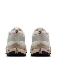Sepatu lari ringan berwarna beige dan abu-abu, menampilkan bagian atas dari kain tekstur, kerah yang empuk, dan sol yang meredam guncangan dengan aksen hitam.