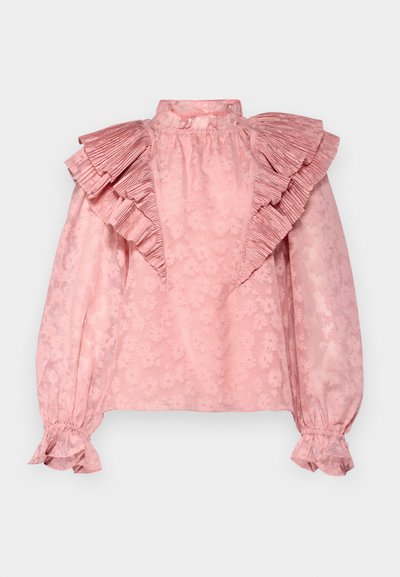 Blusa rosa con cuello alto y mangas abullonadas prominentes. Presenta un patrón floral texturizado y puños fruncidos con acentos de volantes.