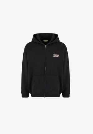 Melna kokvilnas zip-up kapuce ar priekšējo kabatu, aukliņu kapuci un baltu "another cotton" logo uz krūts. Mīksts audums un brīvs piegriezums.