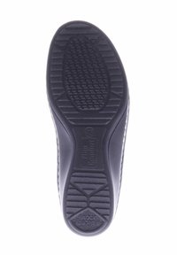 Black rubber shoe sole with textured grip patterns, featuring a raised logo. Rounded heel for stability and flexibility in movement.