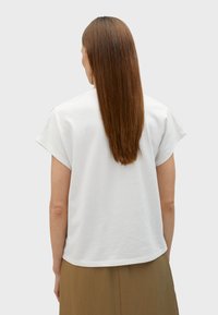 T-shirt bianco a maniche corte in morbido cotone, con vestibilità rilassata e orlo arrotondato, vista dal retro.