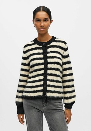 Cardigan rayé blanc et noir avec un col rond, six boutons sur le devant et des poignets côtelés. Fabriqué en tissu tricoté duveteux.