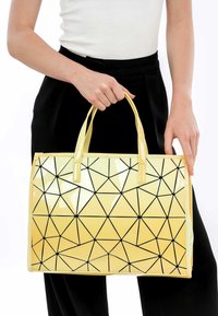 Borsa a telaio rettangolare gialla con motivo geometrico e finitura lucida, dettagli neri. Presenta due manici.