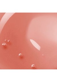 Surface liquide rose brillante avec de petites bulles réfléchissantes regroupées sur le côté gauche sur un fond lisse.