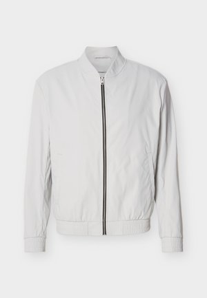 Veste bomber blanche avec fermeture éclair à l'avant, poignets et taille élastiques. Fabriquée en tissu léger avec une texture lisse et sans motifs visibles.