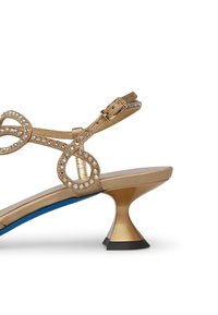 Goldene Sandale mit dekorativen Strassriemen, einer eleganten blauen Innensohle und einem einzigartigen kegelförmigen Absatz mit schwarzem Boden.