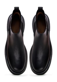 Botas de tobillo de cuero negro con textura suave, paneles laterales elásticos y suelas de goma planas. Presenta costuras mínimas y una pestaña para tirar.