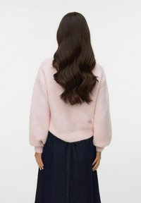 Jasnor�óżowy, puszysty sweter z balonowymi rękawami i prążkowanymi mankietami, w połączeniu z ciemną spódnicą dżinsową, widziane od tyłu.