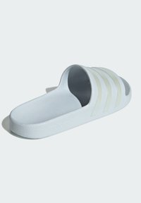 White slide sandal with textured strap featuring three vertical stripes, soft footbed, and embossed logo on the outsole.
