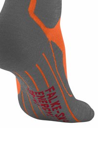 Szara skarpetka sportowa z pomarańczowymi akcentami i teksturowanymi wzorami. Na boku znajduje się czerwony napis "Falke SK Energy".