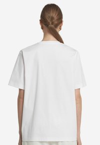 Hvid bomuldsT-shirt med en afslappet pasform, korte ærmer og rund halsudskæring. Stoffet ser glat og udekoreret ud.