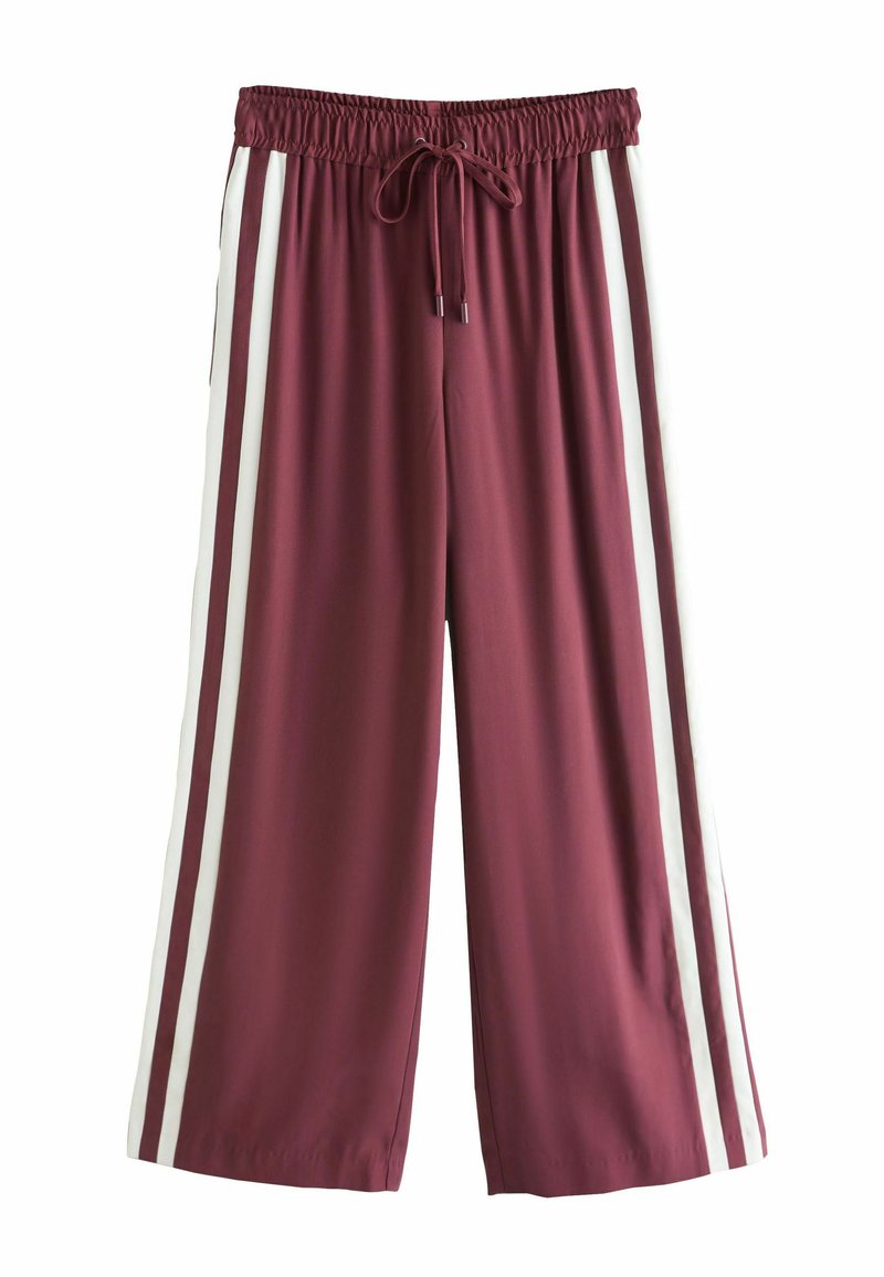 Pantalon bordeaux à jambes larges avec une taille élastique à cordon de serrage et deux bandes verticales blanches sur les côtés. Tissu lisse et léger.