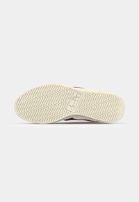 White rubber sole with a zigzag pattern, featuring a logo. Accented with red on the sides and a textured upper part.