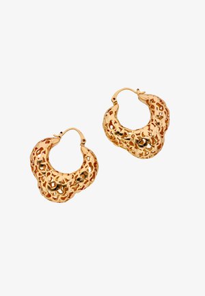 Pár kalapált textúrájú arany karika fülbevaló, szabálytalan áttört mintával és zsanéros kapcsokkal, fehér háttéren.