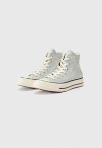 Heledad sneakers heledast halli kangast, millel on tikitud tähed, heledast valgest paelad ja valge kummist tald, millel on mustad aktsendid.
