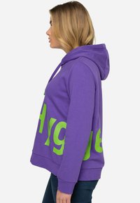 Paarse hoodie van katoen, met een grote groene "Hygiene" grafiek op de voorkant, voorzien van een trekkoordkap en geribde manchetten.
