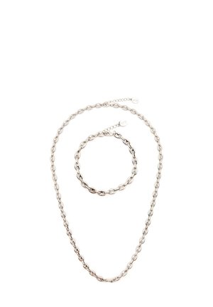 Satelit halsband och armband i silverfärgad metall med oval länkdesign. Halsbandet är längre och båda har justerbara stängningar.