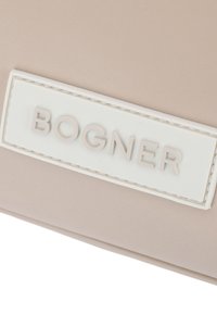 Sac en tissu beige avec une étiquette en relief blanche portant l'inscription "BOGNER", mettant en avant une texture lisse et un design minimaliste.