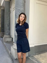 Donkerblauw katoenen t-shirt met logo en bijpassende donkerblauwe katoenen shorts, voorzien van een elastische tailleband en een comfortabele, losse pasvorm, geplaatst tegen een marmeren achtergrond.