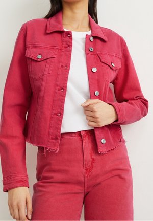 Rød denimjakke med cropped design, to brystlommer, metalliske knapper og frynset kant, parret med en hvid T-shirt og matchende bukser.