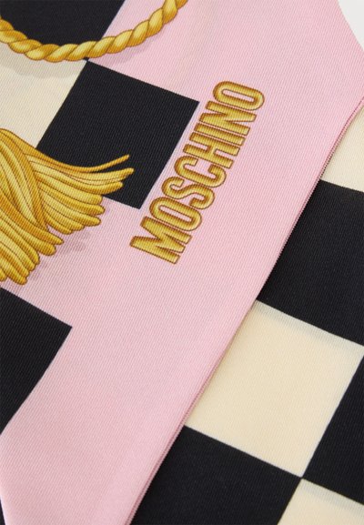 Tissu rose avec motif de corde et pompon dorés et texte doré "Moschino" sur fond à carreaux noir et blanc.