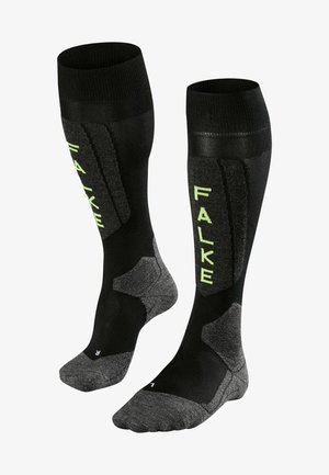 Knee-length black socks with textured panels and lime green "FALKE" branding. Reinforced heel and toe with dark gray accents.