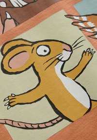 Illustration av en tecknad mus med en gulbrun kropp, vit mage och rosa öron, placerad mot olika texturerade pastellbakgrunder.