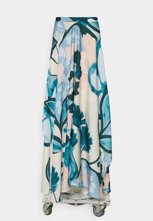 Longue jupe fluide avec de grands motifs floraux bleus et turquoise sur fond blanc et rose pâle, présentée sur une plateforme à roulettes.