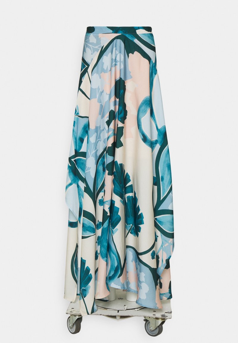 Longue jupe fluide avec de grands motifs floraux bleus et turquoise sur fond blanc et rose pâle, présentée sur une plateforme à roulettes.