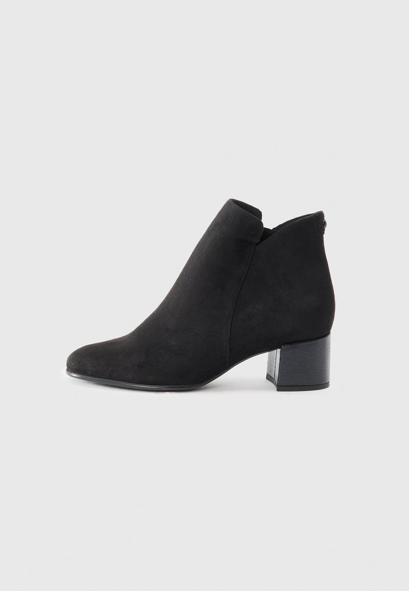 Bottine en daim noir avec talon bloc et bout légèrement pointu, présentée sur un fond gris clair.