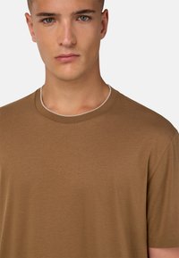 Rudų trumpų rankovių marškinėliai su apvalia iškirpte ir vienspalviu tekstūra, pagaminti iš švelnios medžiagos, demonstruojantys paprastą, minimalistinį dizainą.