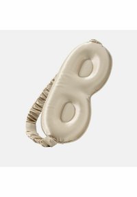 Pehmeä beige satiininen unimaski, joka on muotoiltu soikeaksi ja jossa on kaksi silmille tarkoitettua aukkoa. Maska sisältää kerättyä kangasta säädettävää sovitusta varten.