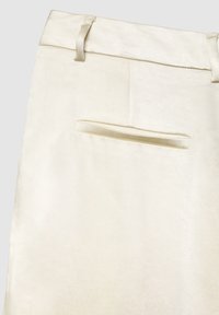 Jupe beige en tissu lisse, dotée d'une ceinture plate avec passants et d'une unique poche arrière sans quincaillerie visible.