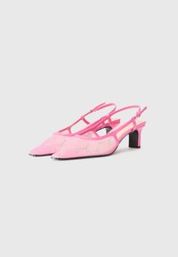 Tacones rosa con tira trasera y puntera en punta, decorados con patrones de strass y con un tacón cuadrado negro. Fabricados con material suave.
