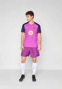 Fialový futbalový dres Nike s modrými rukávmi, uprostred so zeleným logom Spotify. Dopĺňa ho fialové šortky, biele ponožky a čierne kopačky.