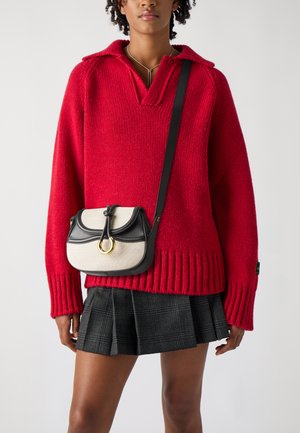 Rød strikket genser med V-hals og ribbestrikket kant, samt en svart-og-beige crossover-veske med en gullringdetalj og snorinnlegg.