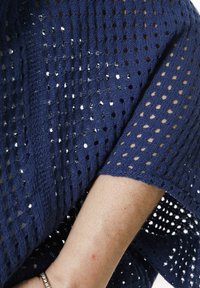 Marineblaues gestricktes Oberteil mit offenem Gewebe und kleinen Löchern, kurzen Ärmeln und einer lässigen Passform. Akzentuiert mit strukturierten Linien.