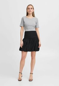 Graues, geripptes kurzärmliges Oberteil, das mit einem schwarzen, voluminösen Rock kombiniert ist. Der Rock hat eine taillierte Taille und Faltendetails.