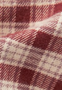 Tissu en laine douce avec un motif à carreaux rouge et beige présentant de grands et petits carrés ainsi que des rayures diagonales.