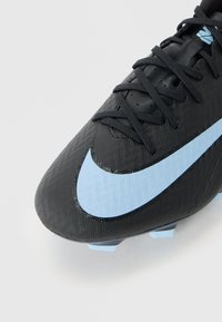 Svart fotbollssko med en texturerad ovandel, med en ljusblå Nike Swoosh. Snörningsdesign och formade dobbar på sulan för grepp.