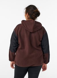 Hooded jacket featuring a brown fleece body and black nylon sleeves. Soft texture, relaxed fit, and visible stitching detail on sleeves.