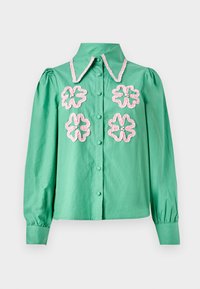 Camisa verde menta con un cuello estructurado, adornada con bordados florales rosas en el delantero y cierre de botones. Mangas largas y abullonadas.
