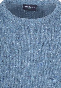 Blauwe gebreide trui met een ronde hals, een gestructureerd weefpatroon en kleine witte en donkerblauwe vlekjes door de stof. Merkentlabel aan de binnenkant.