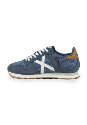 Zapatilla deportiva azul que presenta una mezcla de materiales de ante y malla, acentos en blanco, diseño con cordones y una suela de goma texturizada.