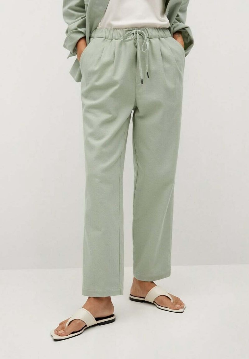 Světlé zelené, lehké kalhoty s elastickým pasem, bočními kapsami a zúženým střihem. Spárované s plochými sandály s otevřenou špičkou.