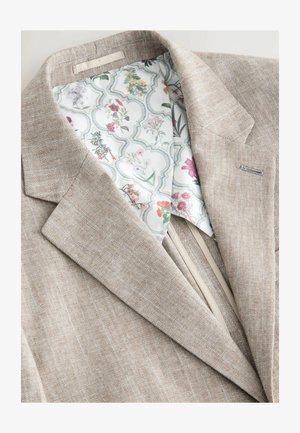 Veste de costume en lin beige avec un doublure à motif floral. Présente un extérieur texturé et une coupe moderne avec des revers incurvés.