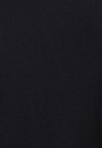 Black knitted fabric texture with visible fine ribbing pattern, showing close-up details of the material structure.