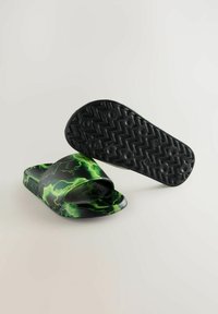 Infradito neri con motivo verde a zig zag sulla parte superiore. Suola piatta con fondo testurizzato e lavorato per una buona aderenza. Materiale sintetico morbido.