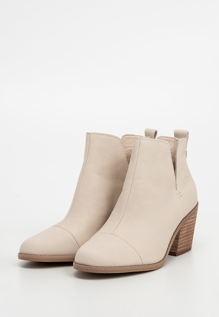 Beige Leder-Stiefeletten mit spitzem Zehenbereich, elastischen seitlichen Einsätzen und einem gestapelten Holzabsatz. Glatte Textur mit minimalen Nahtdetails.