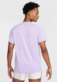 Light purple athletic t-shirt with raglan sleeves, made of moisture-wicking fabric. Features reflective accents on the back and side slits.